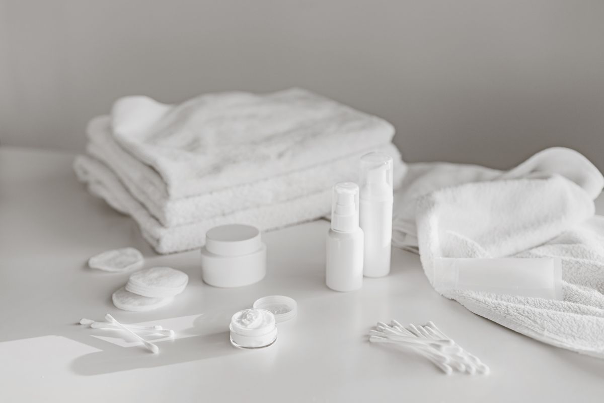 Neat arrangement of white skincare essentials and a folded towel